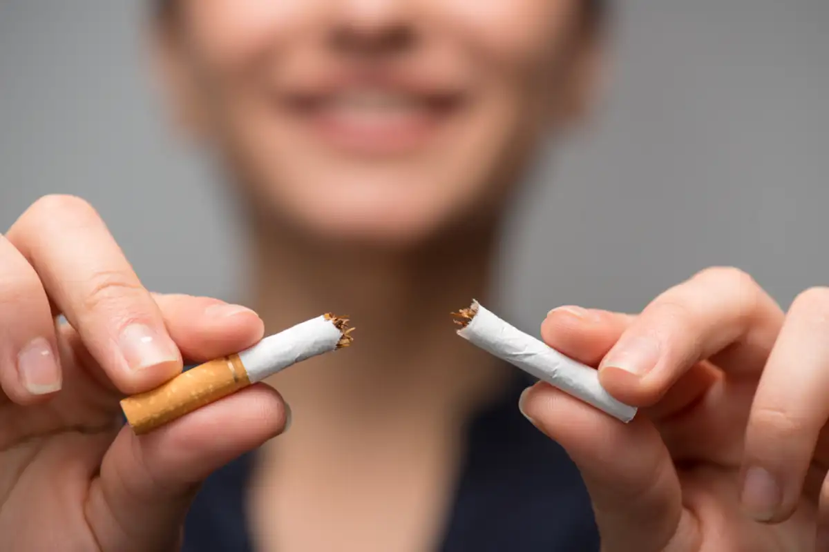 Close up portrait of young woman breaking down cigarette to pieces