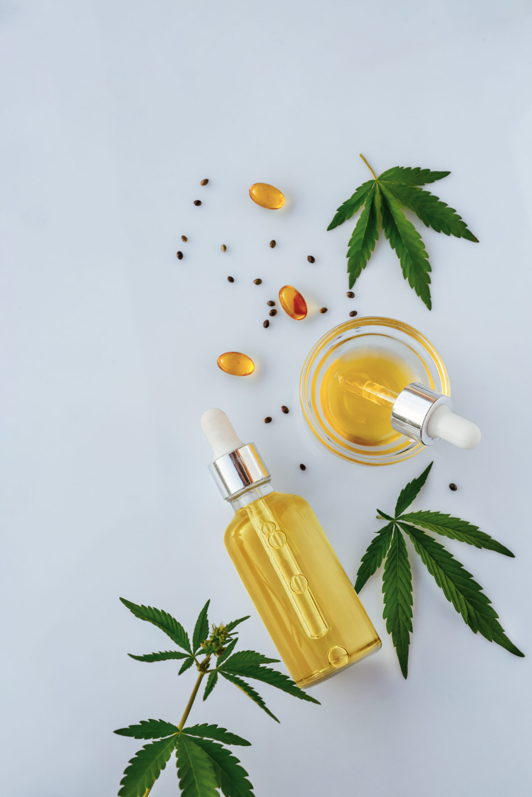 CBD oil in a bottle with a pipette, capsules and marijuana leaves on a white medical background